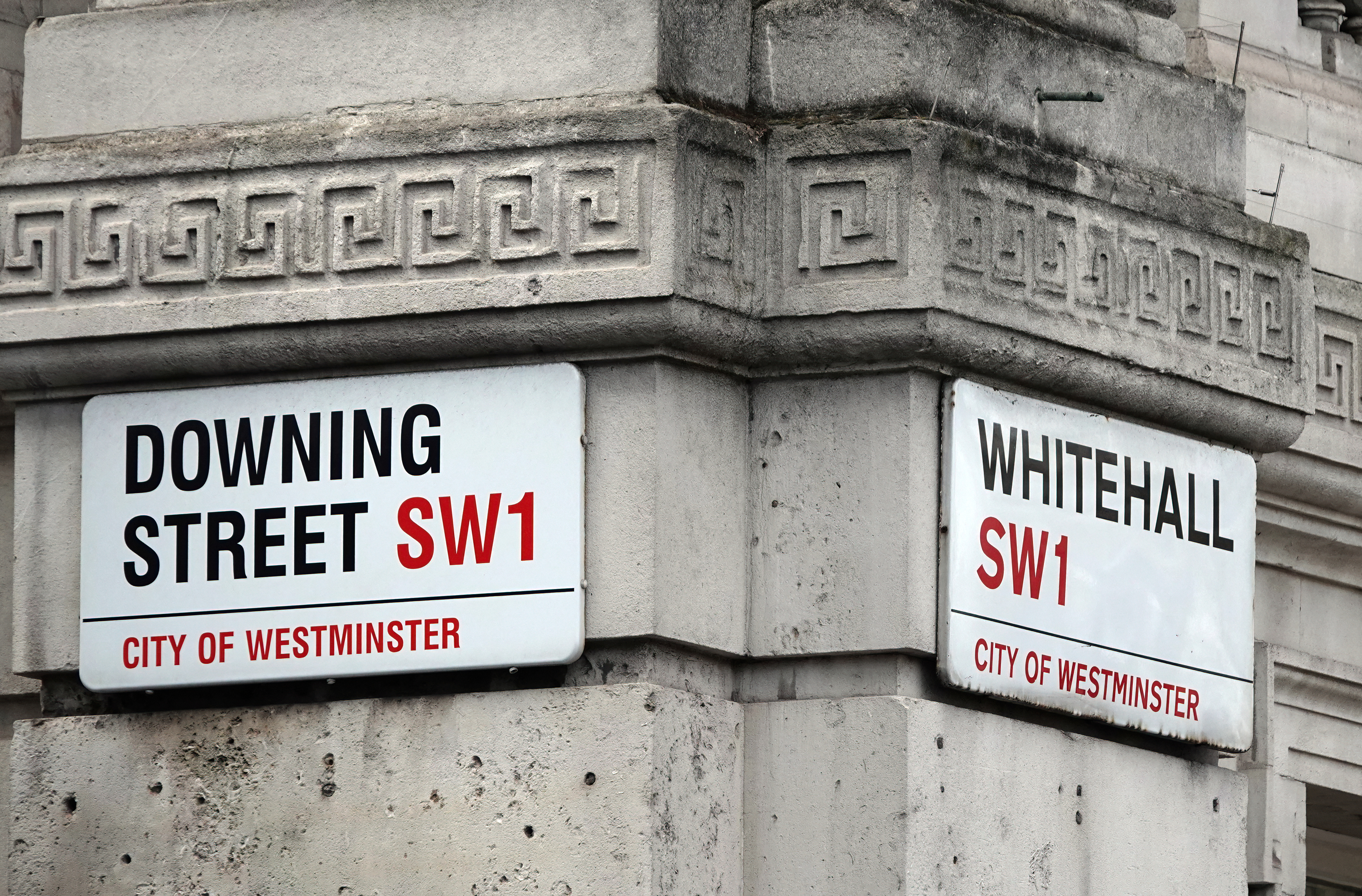 A photograph of Downing Street and Whitehall road signs on a building